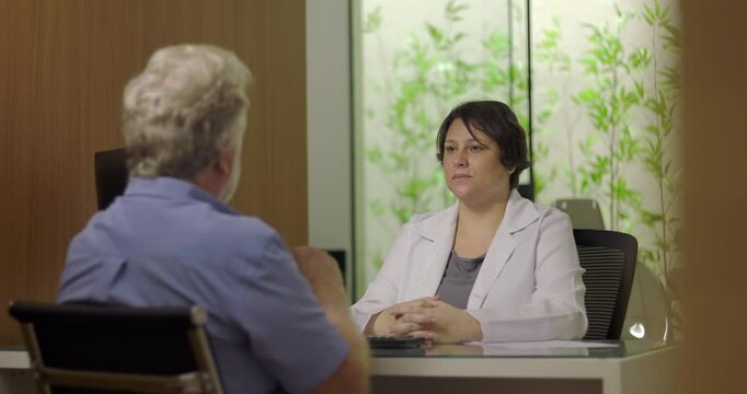 Doctor listening to male patient during consultation in medical office with calm demeanor and attentive body language in professional healthcare environment