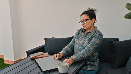 Woman Working on Laptop Outdoors with Coffee and Smartphone Nearby