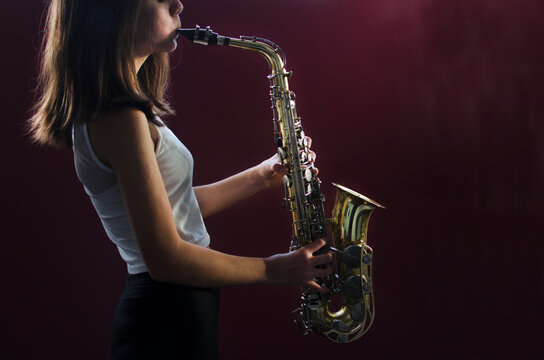 Close-up Side view of a Teenage girl in a vest playing the saxophone