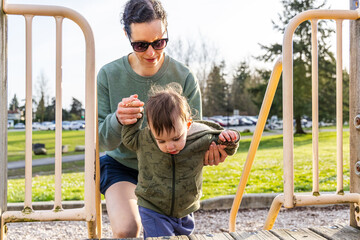 Obraz premium Mother Guiding Toddler Boy at Playground in Burnaby, Vancouver, BC, Canada