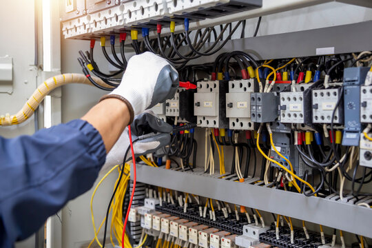 Checking the electrical system, an electrician is using an electric meter to check the electrical system at a control cabinet. for safety