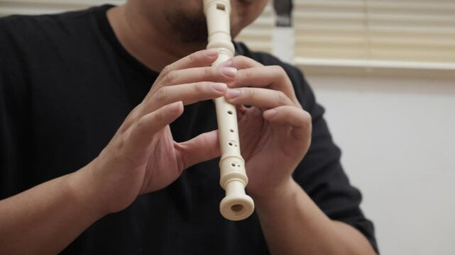 Asian man playing recorder flute, musical instrument