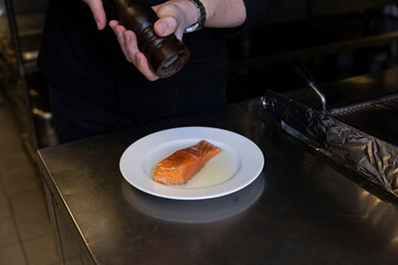 The chef is oiling and salting the salmon and preparing it.