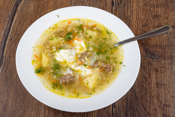 A plate of freshly prepared Leningrad rassolnik soup with beef in a rich golden broth.