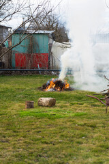 A burning bonfire in the distance. A pile of branches is smoking thick smoke