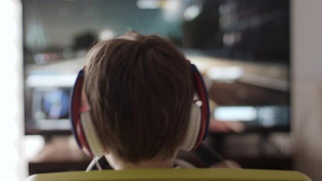 Boy Playing Racing Video Game in Game Console. Child Playing Computer Game in Headphones With Steering Wheel. Gamer With Headset Holding Steering Wheel Playing Video Game. Kid Gambling Addiction.