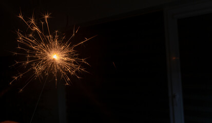 A sparkler burns against a dark background