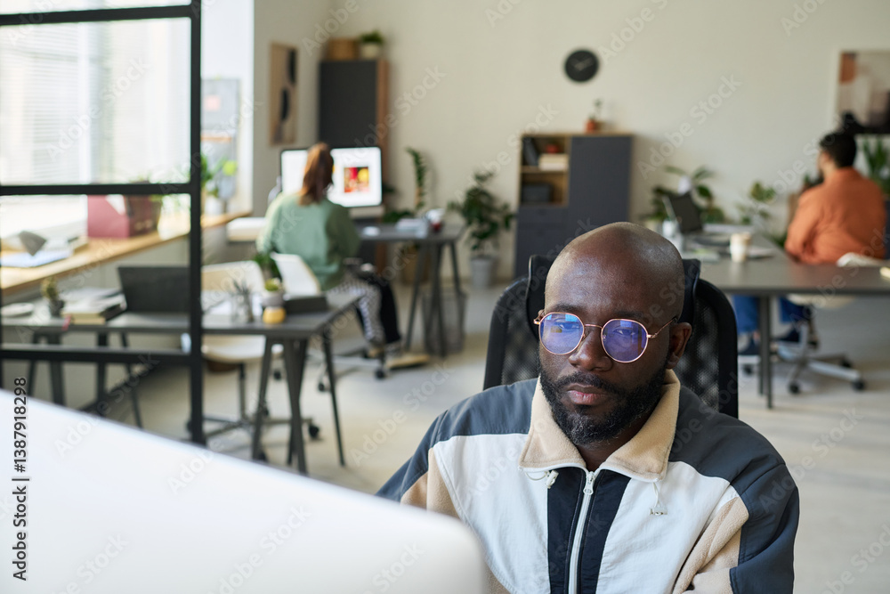 Poster Bald African American software developer looking at screen of desktop computer while testing new product or decoding data