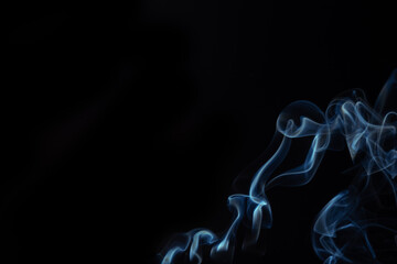 Blue smoke swirls in abstract form on black background. Concept of mystery and creativity. Swirling, writhing smoke to overlay on your photos.