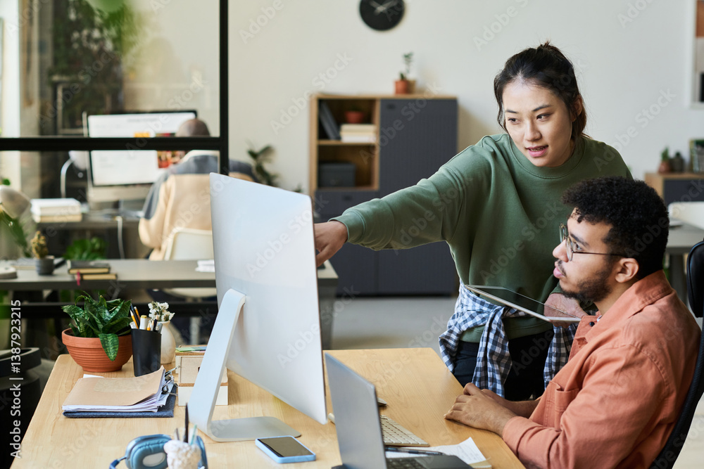 Poster young confident chinese woman with tablet pointing at computer screen while explaining information t