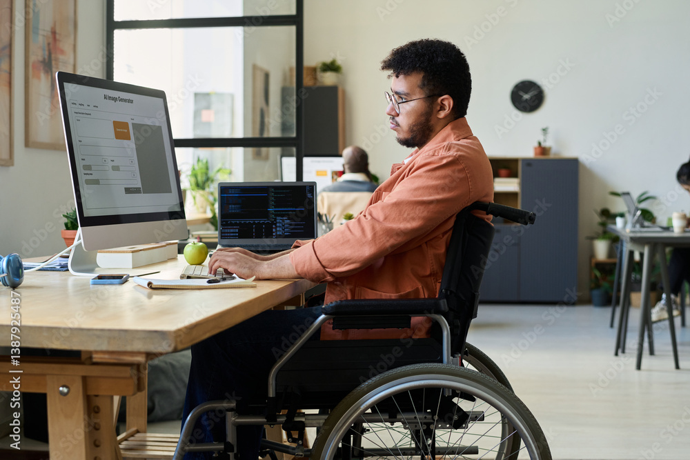 Aufkleber Side view of young multiethnic man with disability sitting in wheelchair and typing on keyboard while using AI image generator