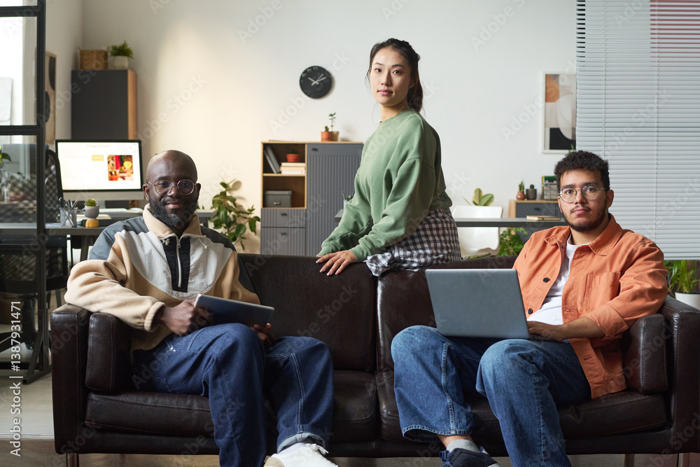 Aufkleber team of young intercultural software developers with gadgets looking at camera while sitting on blac