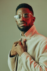 Stylish African American man with glasses in a warm toned coat, exuding confidence against a soft gradient background Fashionable portrait for marketing purposes