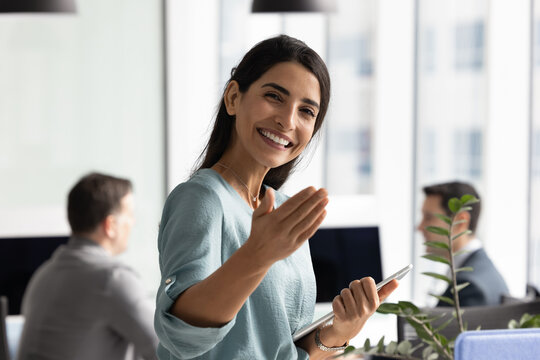 Friendly young Hispanic recruiter woman inviting job candidates to join team. Happy businesswoman welcoming customers, partners for consultation, making hand invitation gesture, smiling at camera