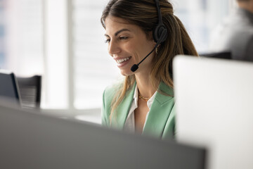 Happy Hispanic customer support service worker speaking at mic of headset on operator workplace,...