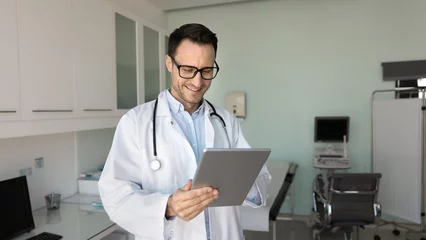 Gordijnen Therapist using tablet in workplace, consulting clinic patient remotely using telemedicine platform, access electronic health records for review history or anamnesis, examine lab, X-rays, or MRI scans © fizkes