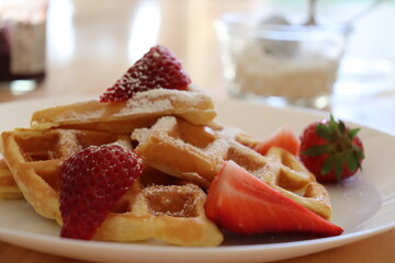 Golden waffles served with ripe strawberries, delicately dusted with powdered sugar
