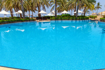 Swimming pool with clear water surrounded by palm trees in one of the best resorts
