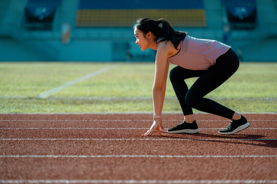 Young Asian athlete preparing for a race on a running track