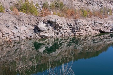 View of a lake with a rocky shore and clear water in a granite quarry.