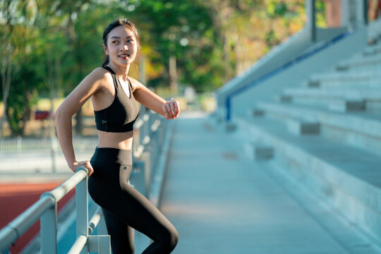 Young sportswoman checking smartwatch during training break in stadium - Powered by Adobe