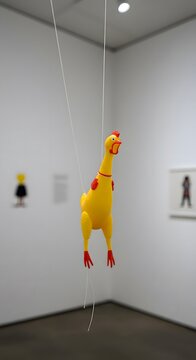 Quirky yellow rubber chicken suspended in an art gallery setting