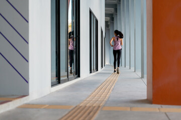 Fototapeta premium Young sportswoman running in a modern building corridor