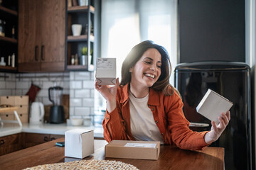 Happy woman holding parcels at home in her kitchen