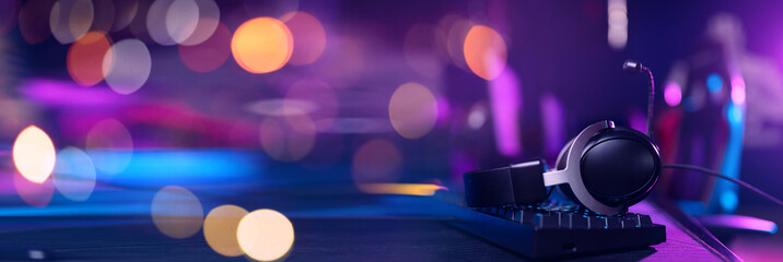 Gaming headset and keyboard in colorful esports arena banner © Parilov