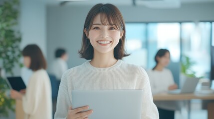 Fototapeta premium Smiling japanese business professional in modern office holding laptop bright environment positive atmosphere
