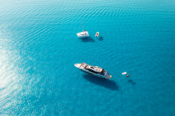 Aerial view of beautiful luxury yacht and boat in blue sea in summer. Sardinia, Italy. Top drone view of speed boat, sea coast, transparent azure water. Travel. Tropical landscape. Yachting. Seascape