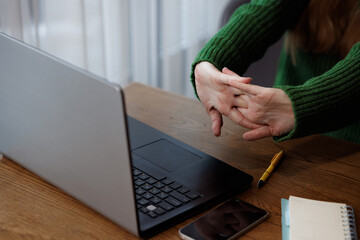 Hands stretch near laptop to reduce stiffness during a work break, healthy ergonomic habits.