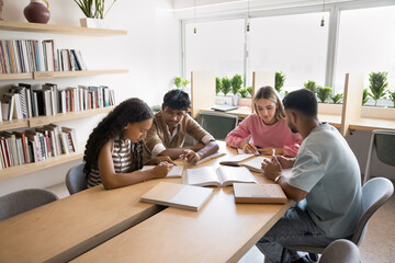 Working on group project. Diverse multiracial gen z students teammates gather at library to...