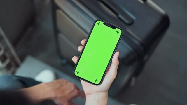 Hands of traveller using mobile smartphone with Green Screen for connecting in airport terminal, using app, checking time schedule, Concept of online taxi order, hotel transfer service.