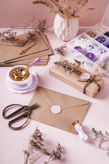 Craft envelope with wax seal and crafting items on pink vertical view