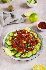 Delicious cucumbers with chili pepper and lime on a plate on the table vertical view