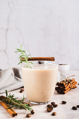 Aromatic coffee with rosemary and cinnamon in a glass on the table vertical view
