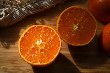 close-up of two slices of an orange on a wooden cutting board in evening sun 