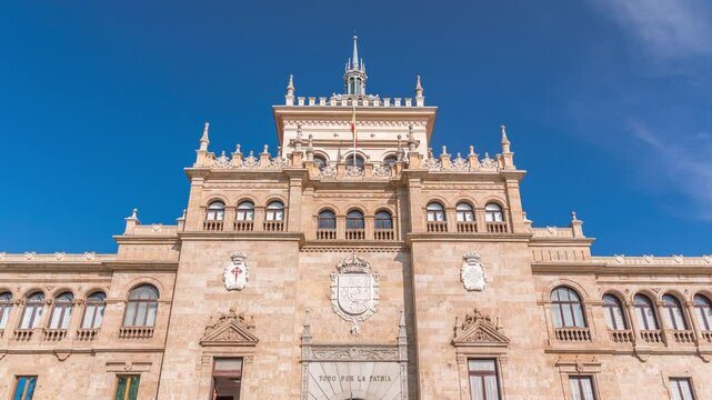 Timelapse of the Cavalry Academy facade in Plaza de Zorrilla, Valladolid, Spain. Historic military building with intricate architecture, surrounded by a busy urban scene under a blue sky with clouds.