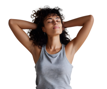 Serene woman with curly hair relaxing with hands behind her head, eyes closed, and wearing a grey tank top against a dark background.
