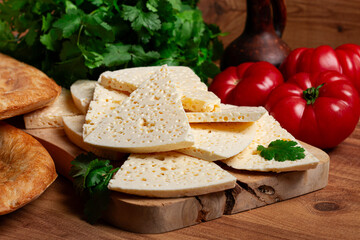 Georgian sliced cheese,on a wooden chopping board, with tomatoes with herbs and lavash, rustic style, Georgian cuisine, no people