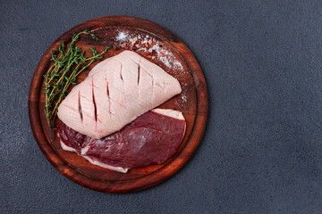 Fresh raw duck breasts, on a wooden chopping board, with herbs and spices, no people