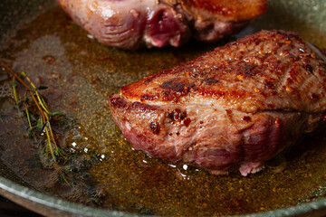 cooking duck breast, in a frying pan, fried, with spices and herbs, close-up, no people,