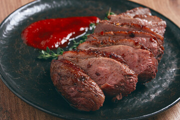 roast duck breast, sliced on a plate, with red sauce, homemade, no people,