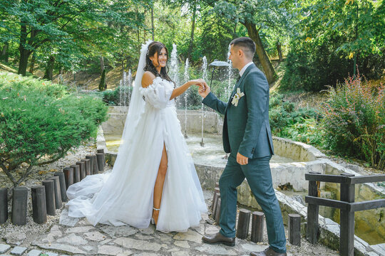 A beautiful bride and groom enjoying a peaceful moment in a scenic outdoor location. The groom holding the bride's hand in a romantic scene on their wedding day. Love is in the air.