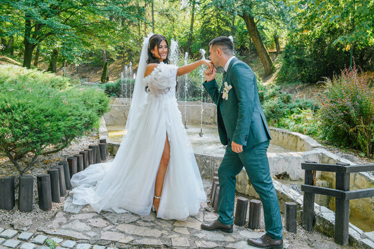 A beautiful bride and groom enjoying a peaceful moment in a scenic outdoor location. The groom kisses the bride's hand in a romantic scene on their wedding day. Love is in the air.