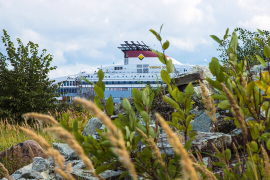 Tallinn, Estonia. September 1st, 2024. Scenic view of Viking XPRS ferry docked in Baltic harbor behind wild grass under cloudy sky. Large cruise ship owned by Viking line based in Finland. Copy space