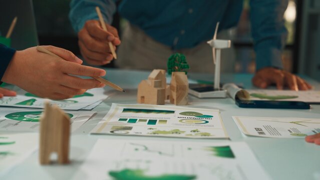 This image captures a collaborative design session where a team focuses on sustainable architecture, showcasing models, sketches, and eco-friendly concepts on a table. SACTR