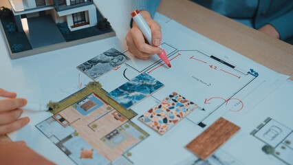 Engaging scene of hands collaborating on an architectural floor plan. Colorful swatches and...