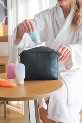 woman hands holding cosmetic travel kit on the coffee table . colorful cosmetic bottles